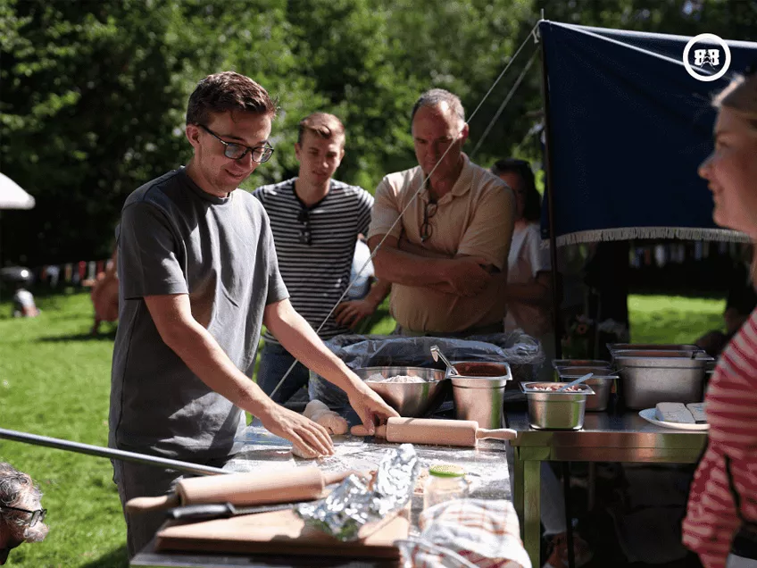 Een bezoeker is de pizza's aan het klaarmaken voor de overige groepsleden